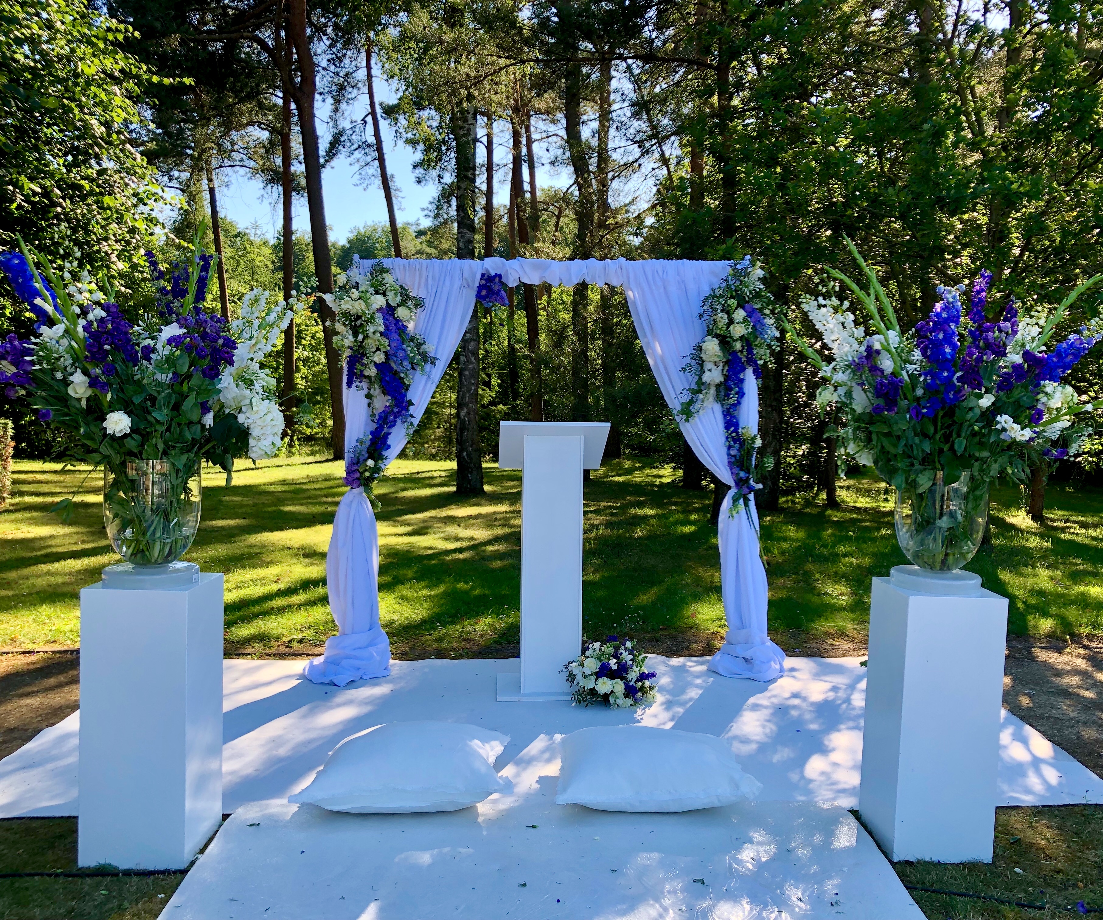 Luxueuze outdoor ceremonie met witte draping en blauwe bloemen